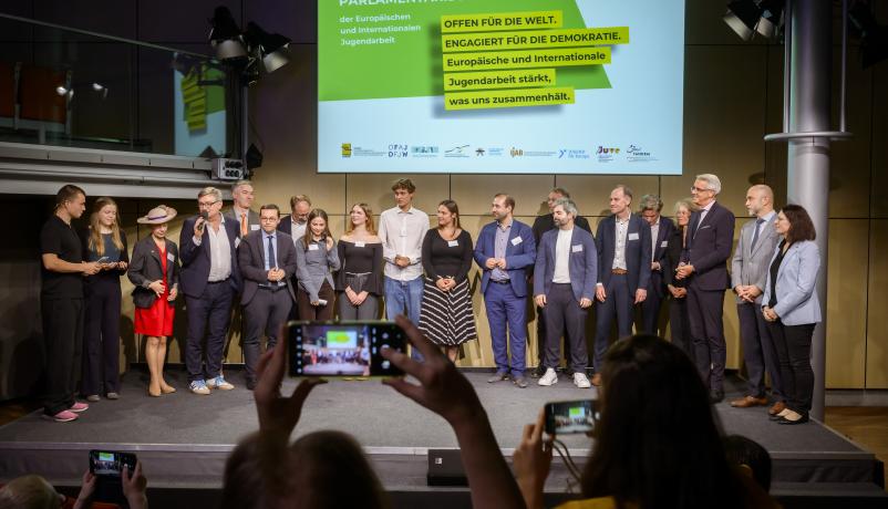 Mitwirkende beim Parlamentarischen Abend - Politiker, Jugendliche, Vertreter:innen der Fach- und Förderstellen – stehen zum Abschluss gemeinsam auf der Bühne.