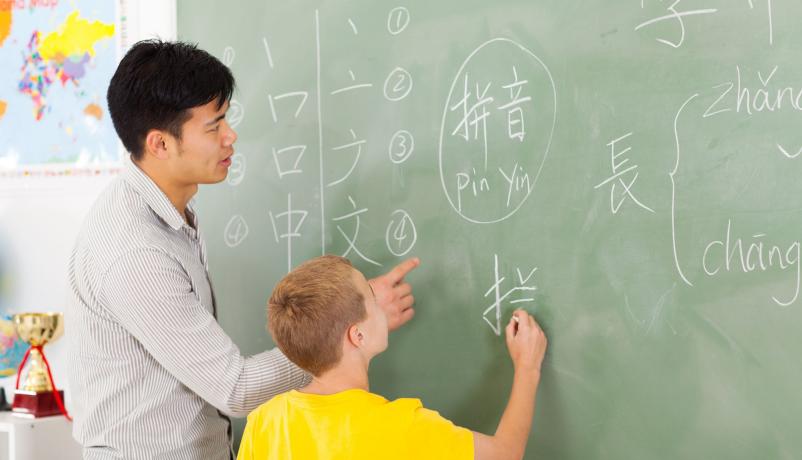Beim Chinesisch-Unterricht Lehrer hilft Schüler beim Schreiben chinesischer Zeichen