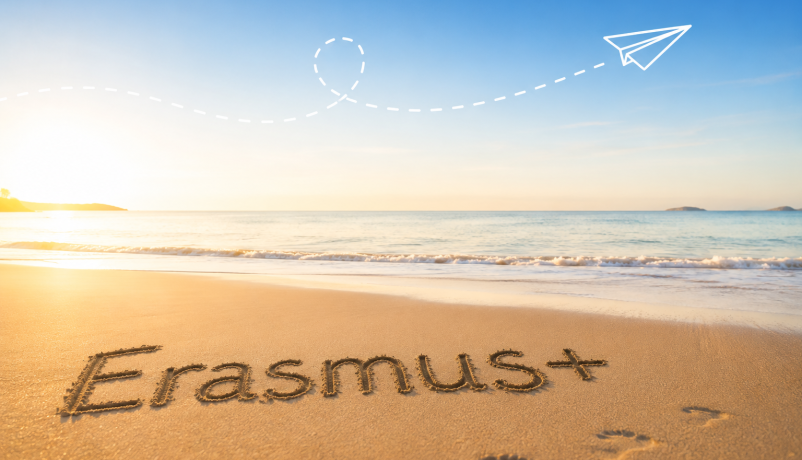 Erasmus+ im Sand geschrieben an einem ruhigen Strand.
