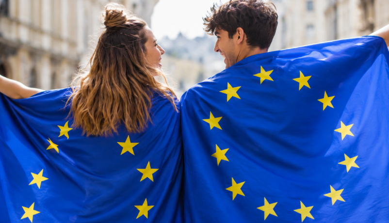 junge Frau und junger Mann tragen je eine Europaflagge - Europa als Perspektive für die Jugend