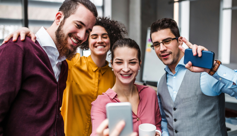 Vier junge Erwachsene an einer Schule im digitalen Austausch per Smartphone