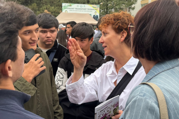 Eine deutsche Teilnehmerin der Fachreise spricht mit mehreren usbekischen Jugendlichen auf der BerufsEXPO in Taschkent.
