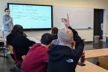 Blick ins Klassenzimmer, während ein Freiwilliger aus Frankreich im Unterricht unterstützt