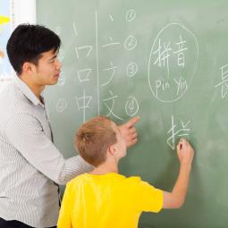 Lehrer hilft Schüler beim Schreiben chinesischer Zeichen