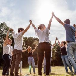 eine Gruppe Jugendlicher steht in einem Park und halten einander freundschaftlich