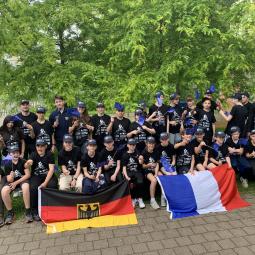 "Aux vélos | Auf die Räder" - deutsch-französische Schülerbegegnung Teilnehmende des Austauschprojekts "Aux vélos | Auf die Räder" sitzen und stehen im Park mit deutscher und französischer Fahne