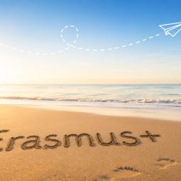 Erasmus+ im Sand geschrieben an einem ruhigen Strand.