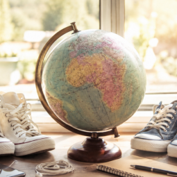 KI-generierte Illustration: Schuhe und ein Globus als Zeichen für Bereitschaft zum Aufbruch in die Welt