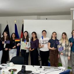 Teilnehmende einer deutsch-französischen Jugendbegegnung präsentieren Ergebnisse in einem Seminarraum mit Flaggen