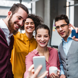 Vier junge Erwachsene an einer Schule im digitalen Austausch per Smartphone