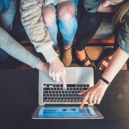 Drei junge Menschen deuten auf einen Laptop-Bildschirm